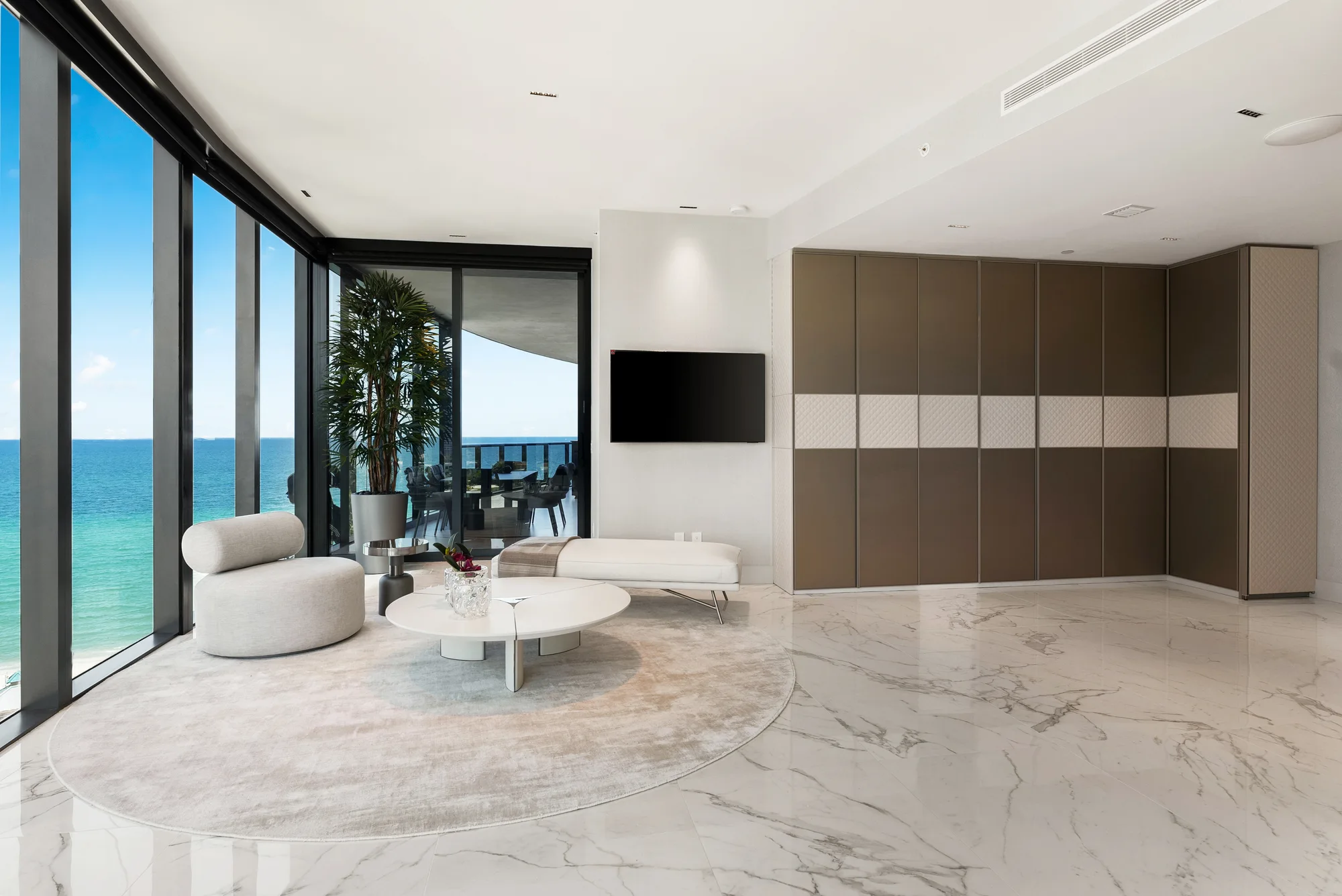 Sunlit contemporary living room with natural stone, warm wood, and ocean views